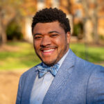 A person in a Carolina blue suit and bow tie poses for a photo.